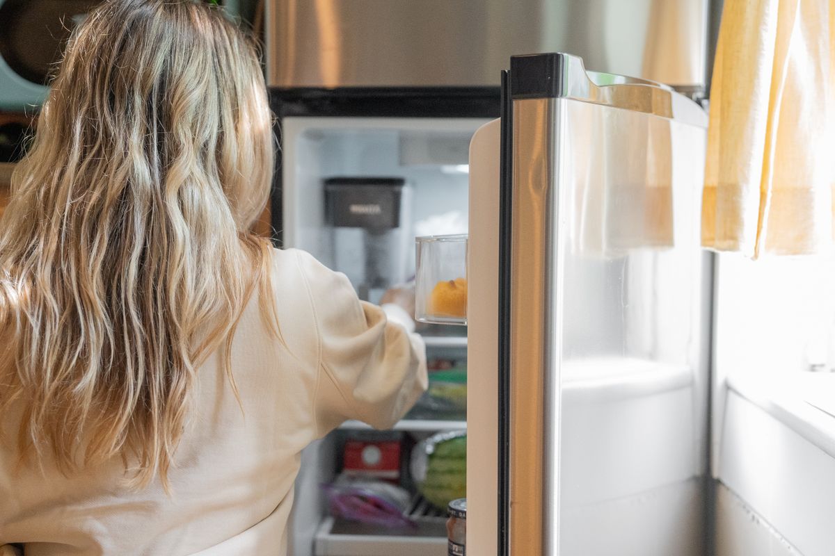 Household refrigerator being opened in a home kitchen