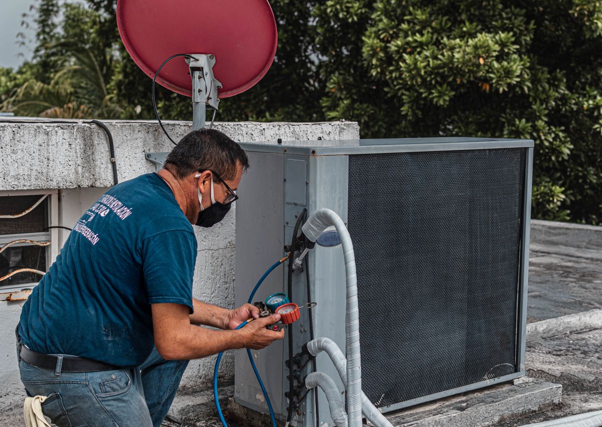 Technician servicing an outdoor air-conditioner condenser unit