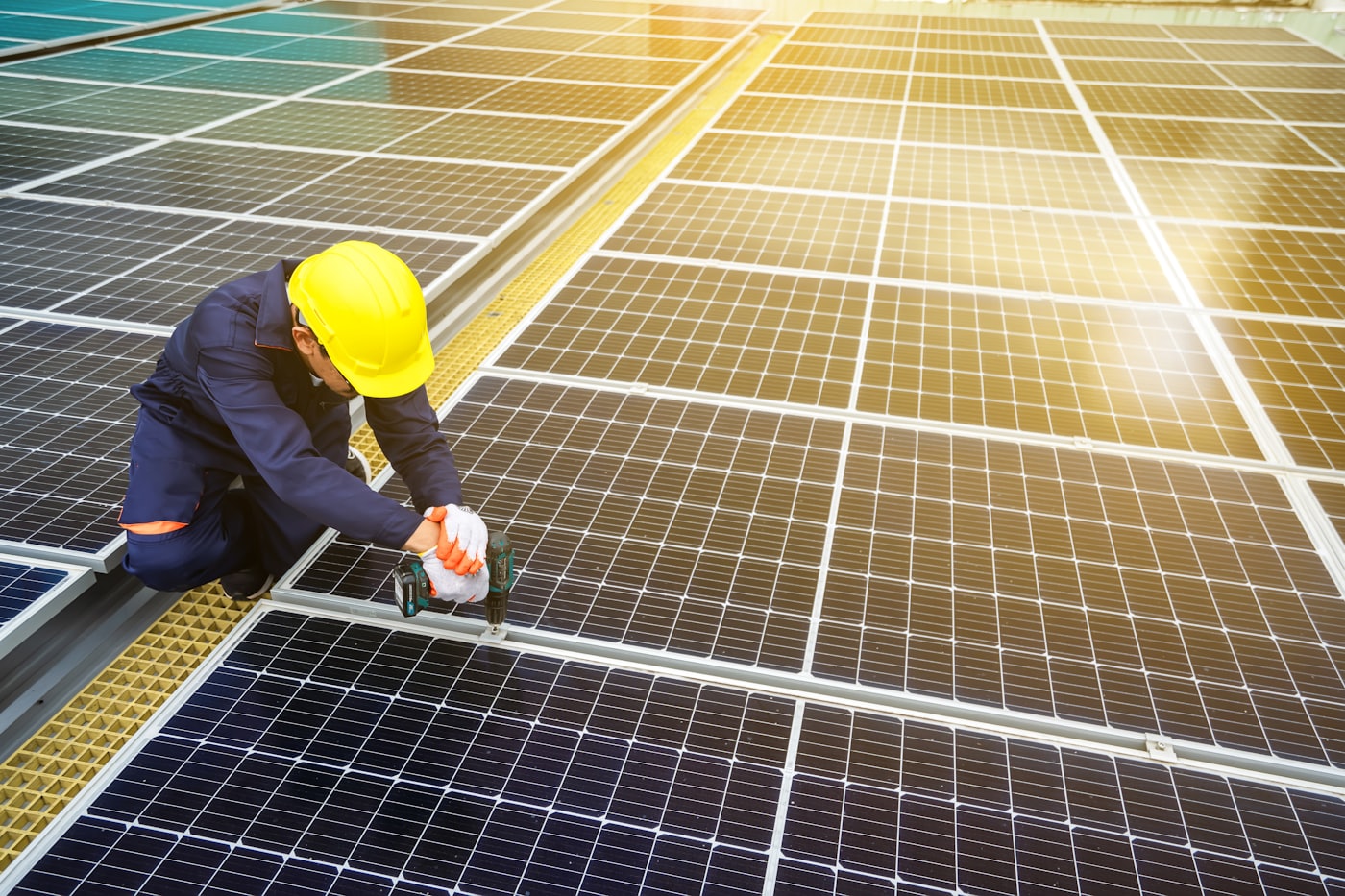 Technician in a hard hat installing a solar panel on a rooftop array